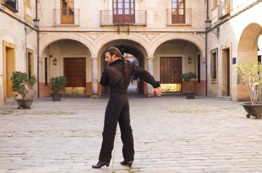 İspanya, Seville 'de sütunları ve balkonları olan bir meydanda uzun saçlı flamenko dansı yapan orta yaşlı bir flamenko. Tutkuyu hisset. Flamenko dans konsepti insanlığın kültürel mirası.