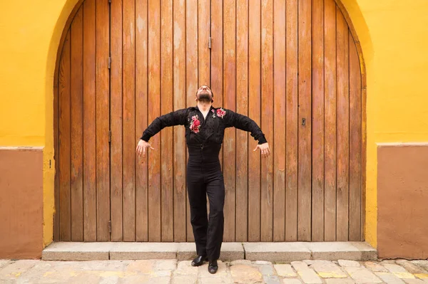 Siyah tişört ve kırmızı güllerle flamenko yapan adam ahşap bir kapının arkasında dans ederken farklı duruşlar sergiliyor. Flamenko dans konsepti insanlığın kültürel mirası. Tutkuyu hisset.