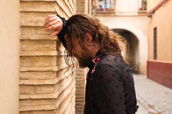 Uzun saçlı, siyah gömlekli ve kırmızı güllü flamenko dansı yapan bir adam kafasını Seville 'in tipik dar bir sokağının duvarına yaslar. Hayal kırıklığı, depresyon, üzüntü, iktidarsızlık, acı, tutku.