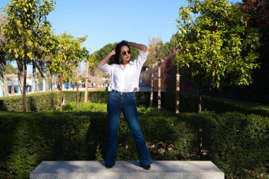 young and beautiful south american tourist in europe, she is on a park bench doing different modeling poses and looking at the camera. Fashion and beauty concept.
