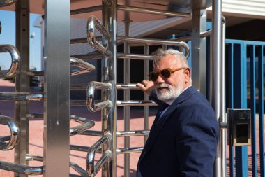 İş adamı ve yönetici olarak çalıştığı binaya sakallı, ceketli, kravatlı ve güneş gözlüklü olgun bir adam giriyor. Konsept patronu, yönetici, ofis, iş ve finans.