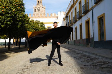 Siyah ve kırmızı ayakkabılar giymiş genç ve yakışıklı çingene bir adamın portresi Seville sokaklarında siyah ve sarı bir boğa güreşçisi peleriniyle dans ediyor. İnsanlığın Flamenko kültürel mirası.