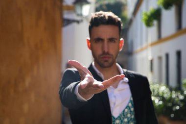 Genç ve yakışıklı çingene adam, siyah beyaz gömlek giymiş, kameraya elini gösteriyor ve seçici bir şekilde odaklanıyor. İnsanlığın Flamenko kültürel mirası.