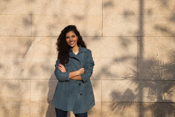 Kahverengi saçlı, kıvırcık burunlu, şık elbiseli güzel bir genç kadın kahverengi arka planda bir süper model olarak poz veriyor. Güzellik ve moda kavramı.