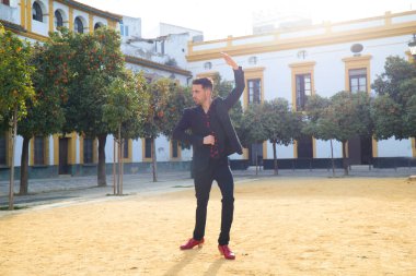 Çingene adam flamenko yapıyor, siyah ve kırmızı ayakkabılar giyip Seville şehrinde portakal ağaçları arasında dans ediyor. İnsanlığın Flamenko kültürel mirası.