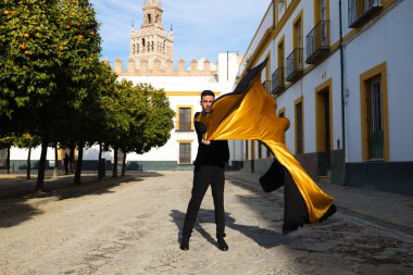 Siyah ve kırmızı ayakkabılar giymiş genç ve yakışıklı çingene bir adamın portresi Seville sokaklarında siyah ve sarı bir boğa güreşçisi peleriniyle dans ediyor. İnsanlığın Flamenko kültürel mirası.