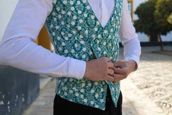 Portrait of young and handsome gipsy man dancing flamenco, dressed in black and green waistcoat dancing flamenco in the typical mediterranean streets of seville. Flamenco cultural heritage of humanity