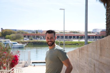 Mavi gözlü yakışıklı genç adam parktaki nehre inen merdivenlerde duruyor. Adam bir Avrupa şehrinde tatilde. Seyahat ve tatil konsepti.