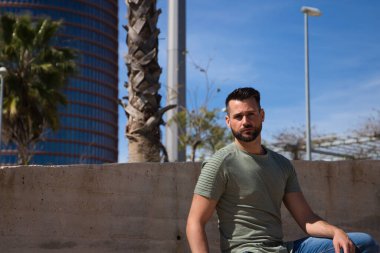 Mavi gözlü yakışıklı genç adam parktaki nehre inen merdivenlerde duruyor. Adam bir Avrupa şehrinde tatilde. Seyahat ve tatil konsepti.