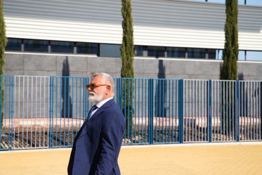 Yakışıklı, olgun, sakallı, ceketli, kravatlı ve güneş gözlüklü adam üniversite kampüsünde öğretim görevlisi olarak çalışıyor. Kavram profesörü, üniversite rektörü..