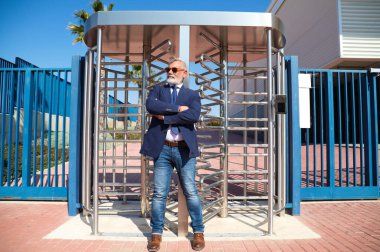 Yakışıklı, olgun, gri saçlı, sakallı, ceketli, kravatlı ve güneş gözlüklü bir adam. Baş muhasebeci ve yönetici olarak çalıştığı ofis binasının girişinde. Olgun iş adamı konsepti