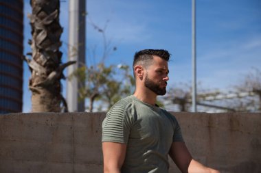 Mavi gözlü yakışıklı genç adam parktaki nehre inen merdivenlerde duruyor. Adam bir Avrupa şehrinde tatilde. Seyahat ve tatil konsepti.