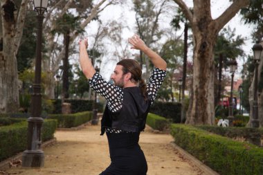 Uzun saçlı ve sakallı, flamenko dansı yapan yakışıklı çingene adam Seville şehrinde bir parkta dans ediyordu. Flamenko, dans, kültür, turizm ve sanat kavramı.