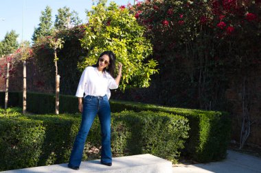 young and beautiful south american tourist in europe, she is on a park bench doing different modeling poses and looking at the camera. Fashion and beauty concept.