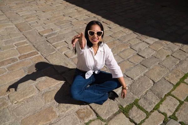 黑发的南美女人正坐在一个典型的地中海城市日光浴的砖地板上 这个女人摆姿势拍照 假日和旅行概念 — 图库照片