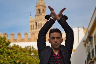 Siyah kastanyetlerle dans eden çingene adam kollarını portakal ağaçlarının arasına uzatarak poz veriyor ve arka planda da Seville Giralda var. İnsanlığın Flamenko kültürel mirası.