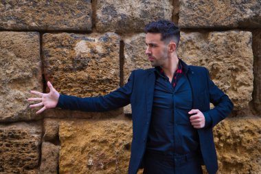 Çingene adam flamenko yapıyor, siyah ve kırmızı ayakkabılar giymiş genç ve yakışıklı taş bir duvarın arkasında poz veriyor ve dans ediyor. İnsanlığın Flamenko kültürel mirası.