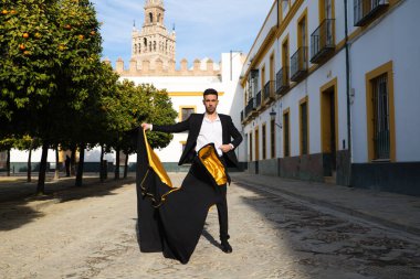 Siyah ve kırmızı ayakkabılar giymiş genç ve yakışıklı çingene bir adamın portresi Seville sokaklarında siyah ve sarı bir boğa güreşçisi peleriniyle dans ediyor. İnsanlığın Flamenko kültürel mirası.