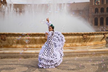Flamenko dansçısı kadın, genç esmer ve güzel tipik İspanyol dansçı çeşmenin önünde sabun köpükleri arasında dans ediyor. İnsanlığın kültürel mirasının Flamenko konsepti.