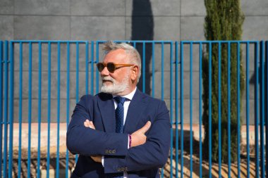 Yakışıklı, olgun, sakallı, ceketli, kravatlı ve güneş gözlüklü adam üniversite kampüsünde öğretim görevlisi olarak çalışıyor. Kavram profesörü, üniversite rektörü..