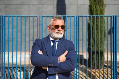 Yakışıklı, olgun, sakallı, ceketli, kravatlı ve güneş gözlüklü adam üniversite kampüsünde öğretim görevlisi olarak çalışıyor. Kavram profesörü, üniversite rektörü..