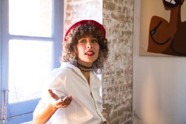 Genç, güzel, girişken bir kadın. Resim ve moda tasarımı sanatına adanmış sanatçı, kafasına kırmızı bir bere takıyor ve fotoğraf için poz veriyor. Girişimci kadın konsepti