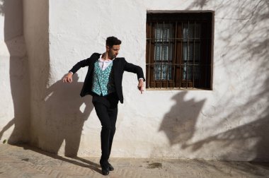 Genç ve yakışıklı çingene adam flamenko dansı yapıyor. Siyah ve yeşil yelek giyip Sevilla 'nın tipik Akdeniz sokaklarında flamenko dansı yapıyor. İnsanlığın Flamenko kültürel mirası