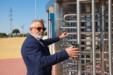 İş adamı ve yönetici olarak çalıştığı binaya sakallı, ceketli, kravatlı ve güneş gözlüklü olgun bir adam giriyor. Konsept patronu, yönetici, ofis, iş ve finans.