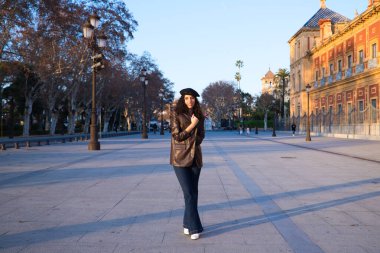 Kıvırcık kahverengi saçlı, siyah şapkalı, deri ceketli, kot pantolonlu ve beyaz çizmeli güzel bir kadın. O, şehri geziyor. Dünya çapında tatil ve turizm kavramı.