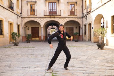 İspanya, Seville 'de sütunları ve balkonları olan bir meydanda uzun saçlı flamenko dansı yapan orta yaşlı bir flamenko. Tutkuyu hisset. Flamenko dans konsepti insanlığın kültürel mirası.