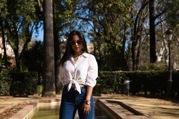 Genç, güzel, esmer bir kadın Seville 'deki bir fıskiyenin kenarında. Güney Amerikalı kadın Avrupa 'da turizm yapıyor ve tatilinin tadını çıkarıyor..