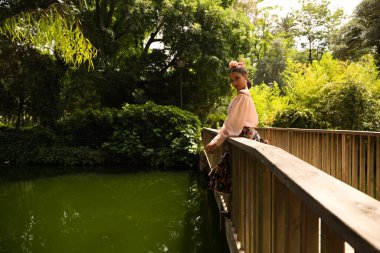 Çiçekli bir etek giymiş, saçı fırfırlı ve çiçekli güzel bir flamenko dansçısı. Tahta bir köprüden eğiliyor. Flamenko kavramı insanlığın kültürel mirası.