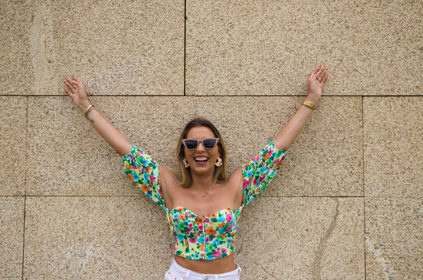 Young beautiful blonde woman with sunglasses leaning against a brown wall in different postures and gestures, happy, sad, depressed, hateful, tired. Concept expressions