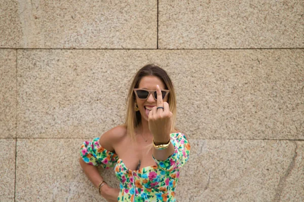 Young beautiful blonde woman with sunglasses leaning against a brown wall in different postures and gestures, happy, sad, depressed, hateful, tired. Concept expressions