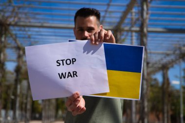 Adam elinde tutuyor savaş işaretini ve Ukrayna bayrağını. O, kameraya afişi gösteriyor. Dünyada insan hakları ve barış kavramı.