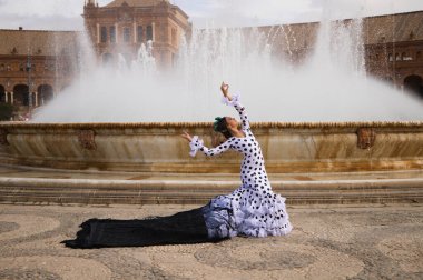 Dişi flamenko dansçısı, genç esmer ve güzel tipik İspanyol dansçı Seville Meydanı 'ndaki bir fıskiyenin önünde siyah bir şalla dans ediyor. Flamenko dünya kültür mirası konsepti.
