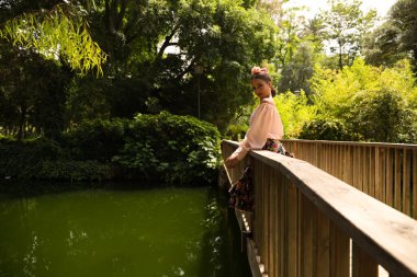 Çiçekli bir etek giymiş, saçı fırfırlı ve çiçekli güzel bir flamenko dansçısı. Tahta bir köprüden eğiliyor. Flamenko kavramı insanlığın kültürel mirası.