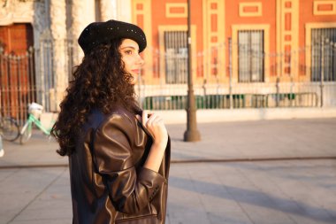 Kıvırcık kahverengi saçlı, siyah şapkalı, deri ceketli, kot pantolonlu ve beyaz çizmeli güzel bir kadın. O, şehri geziyor. Dünya çapında tatil ve turizm kavramı.