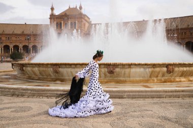 Dişi flamenko dansçısı, genç esmer ve güzel tipik İspanyol dansçı Seville Meydanı 'ndaki bir fıskiyenin önünde siyah bir şalla dans ediyor. Flamenko dünya kültür mirası konsepti.