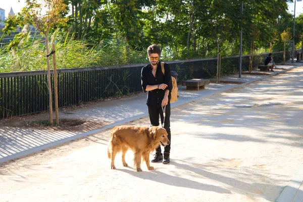 young latin man with sunglasses and beard and his brown golden retriever dog walking in the streets of a big european city. Concept pets, animals, dogs, love to retriever pets.