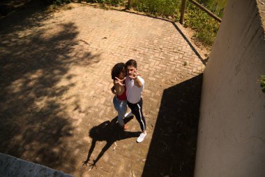 Meydanda dans eden bir çift Latin ve bachata dansçısı. Resim yukarıdan çekiliyor ve kameraya bakıyorlar ve ellerini uzatıyorlar. Onlar yakışıklı bir adam ve güzel bir kadın..