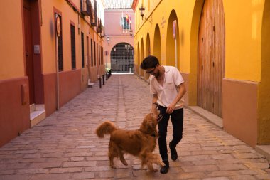 young latin man with sunglasses and beard and his brown golden retriever dog walking in the streets of a big european city. Concept pets, animals, dogs, love to retriever pets.