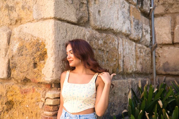 セビリアの本当のアルカサレスの石の壁にカジュアルな服を着て 異なる表情やポーズを作ります 彼女は休日を楽しんでいる — ストック写真
