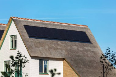 Yeni bir evin sazdan yapılmış çatısına güneş panelleri yerleştirildi