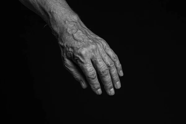 Old man hand on a black background. Black and white.