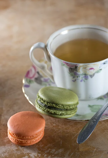 Kolorowe makaroniki francuskie i filiżankę herbaty na drewnianym stole, selecti — Zdjęcie stockowe