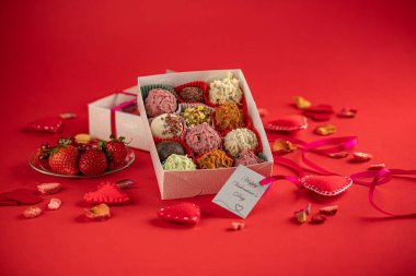 Sevgililer günü çikolataları, hediye kutusu ve kırmızı arka planda kırmızı kurdele..