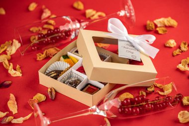 Sevgililer günü çikolataları, hediye kutusu ve kırmızı arka planda kırmızı kurdele..