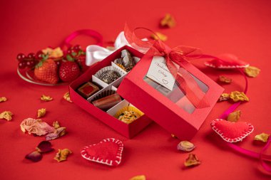 Sevgililer günü çikolataları, hediye kutusu ve kırmızı arka planda kırmızı kurdele..