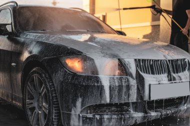 Arabasını yıkayan bir adam. Arabasıyla ilgilenen genç bir çocuk..